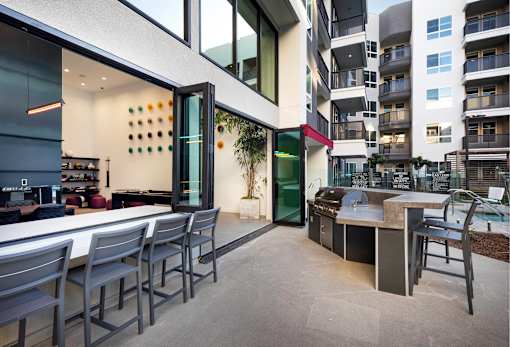 A modern outdoor kitchen area with a bar and chairs