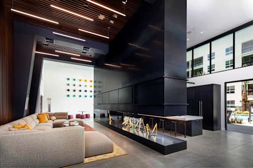 A modern living room with a long white couch and a black and white striped rug.