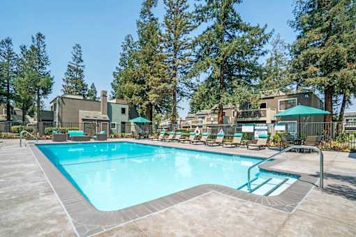 A swimming pool surrounded by trees and buildings.