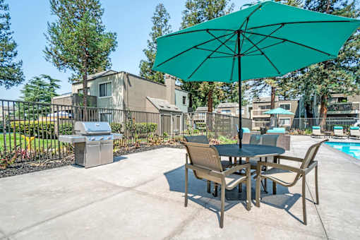 A patio with a table and chairs and an umbrella.
