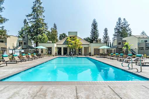 A large swimming pool in front of a building surrounded by trees.