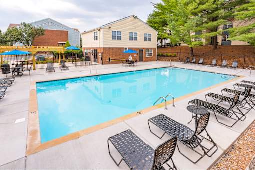 A pool surrounded by chairs and tables.