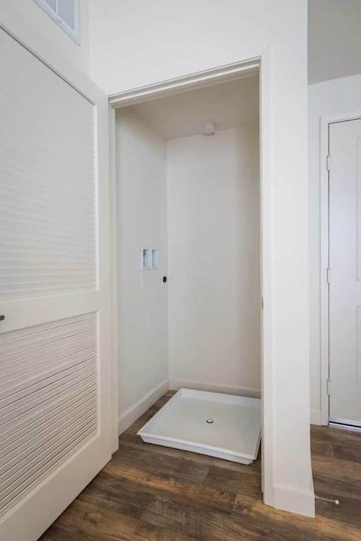 A white door is open to a small white bathroom.