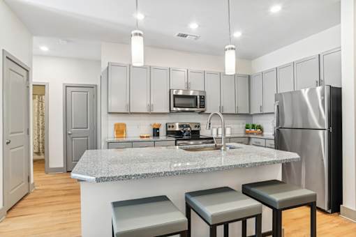 A kitchen with a granite countertop and stainless steel appliances.