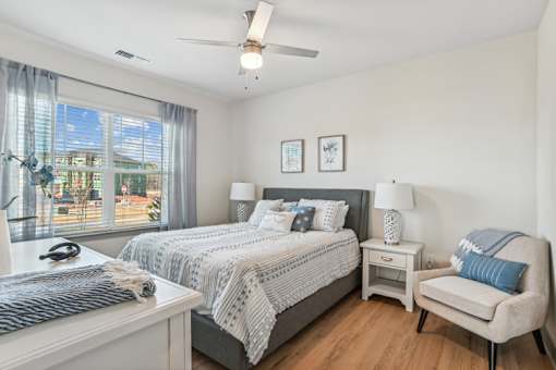 A bedroom with a large bed, a chair, and a ceiling fan.