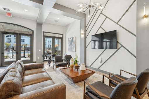 A living room with a brown leather couch and a flat screen TV mounted on the wall.