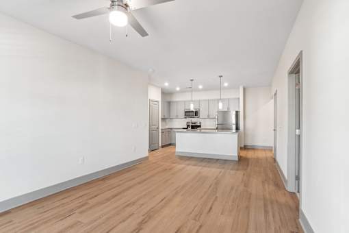 A room with a kitchenette and a ceiling fan.