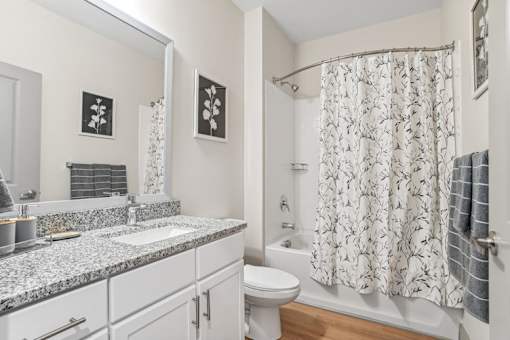 A bathroom with a white toilet, sink, and shower curtain.