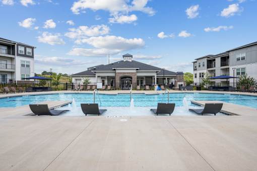 A large swimming pool with lounge chairs and a building in the background.