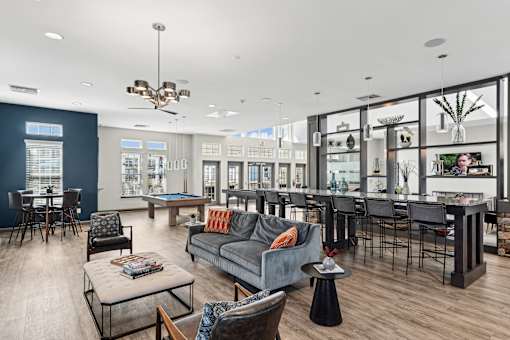 A residential lounge area with a grey couch, an island countertop, and barstool chairs at Parkstone at Knightdale apartments for rent in Knightdale, NC.