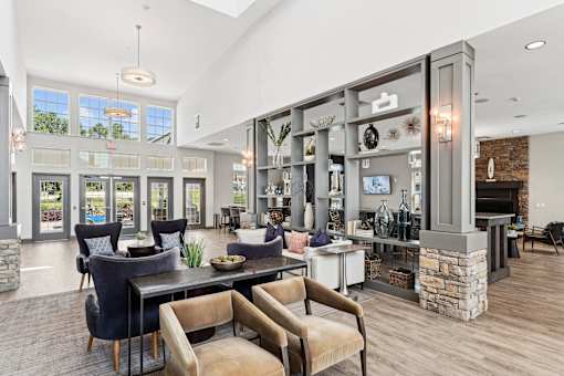 A residential clubhouse with chairs, tables, and a couch at Parkstone at Knightdale apartments for rent in Knightdale, NC.