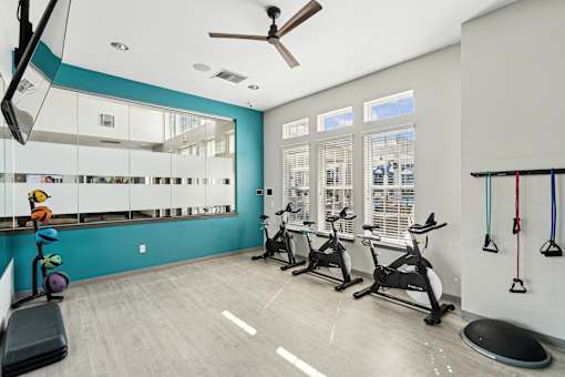 A gym with a mirror, exercise equipment, and a fan.