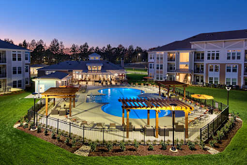 A large swimming pool surrounded by a fence and a gazebo in the middle of a grassy area.