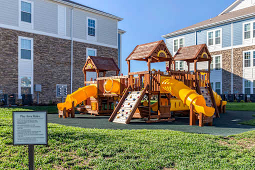 A playground with a yellow slide and a brown roofed structure.