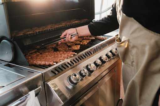 A person is cooking meat on a grill.