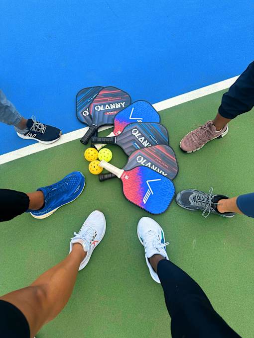 A group of people standing around a paddle ball game.