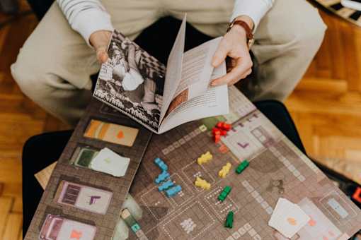 A person is reading a book with a board game in front of them.