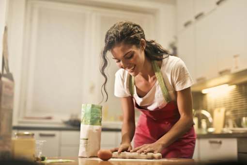 A woman in a red apron is cutting onions in a kitchen.