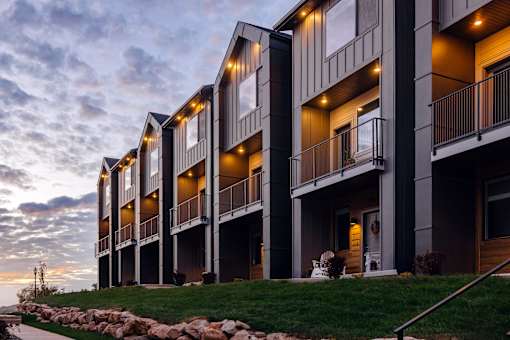 A modern apartment building with balconies and lights on.