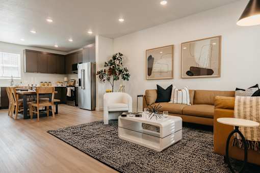 A modern living room with a white sofa, a coffee table, and a dining table with chairs.