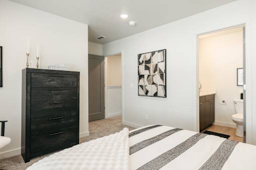 A bedroom with a black dresser and a white bedspread.