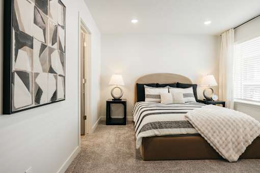 A bedroom with a large bed and a painting on the wall.