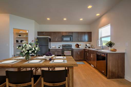 A kitchen with a table set for two with a vase of flowers on it.
