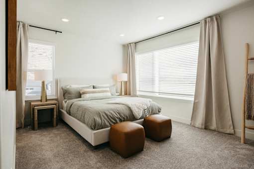 A bedroom with a large bed, two lamps, and a wooden floor.