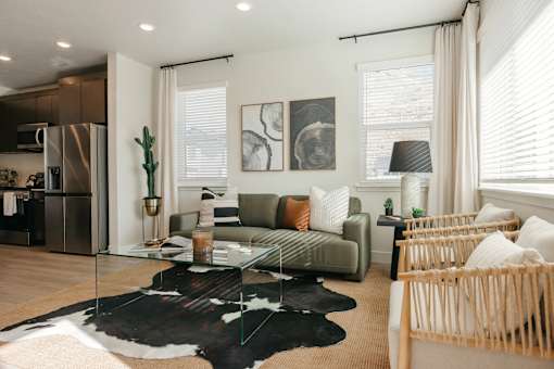 A modern living room with a glass coffee table and a cowhide rug.