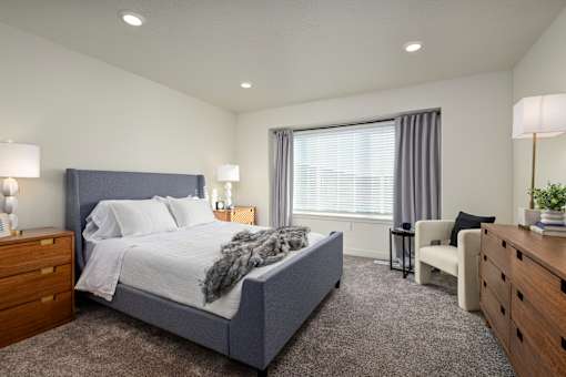A bedroom with a large bed, a chair, and a nightstand.