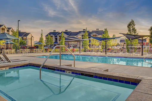 A swimming pool with a diving board in the foreground and a resort in the background.