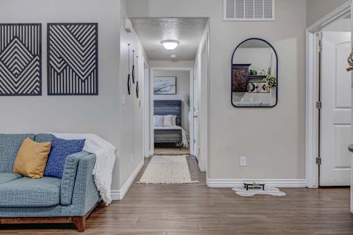 A hallway with a blue couch and a rug.