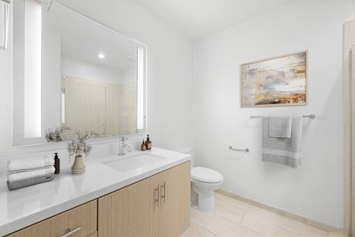 A bathroom with a toilet, sink, and mirror.