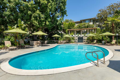 a swimming pool with lounge chairs and umbrellas next to a hotel at Orange Grove Circle, Pasadena, California