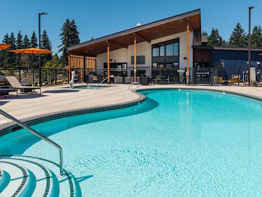 A swimming pool in front of a building with a person standing in the background.