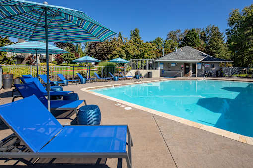 our resort style swimming pool with blue chairs and umbrellas