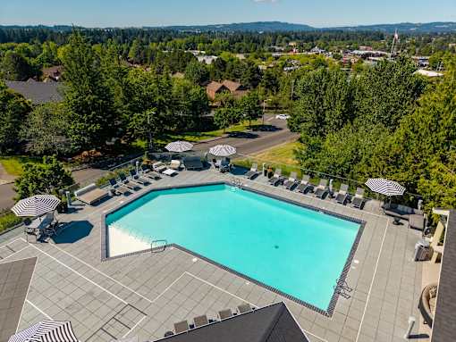 A large swimming pool surrounded by lounge chairs and umbrellas.
