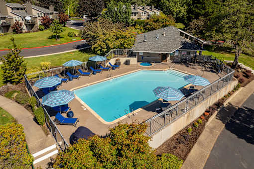 an aerial view of a swimming pool with blue chairs and umbrellas around it