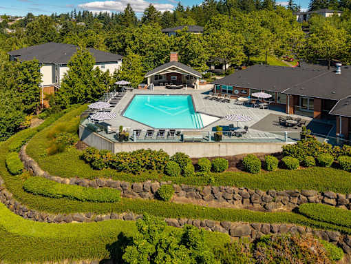 A large backyard with a swimming pool and a stone wall.