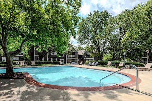 A small pool surrounded by trees and chairs.