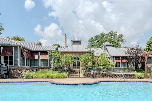 A pool in front of a house with a fence around it.