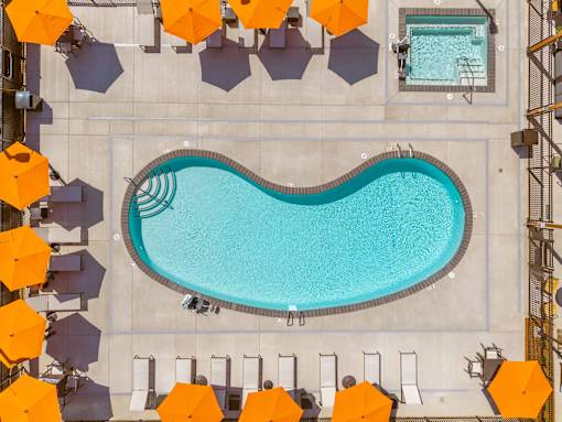 A large swimming pool surrounded by orange umbrellas.