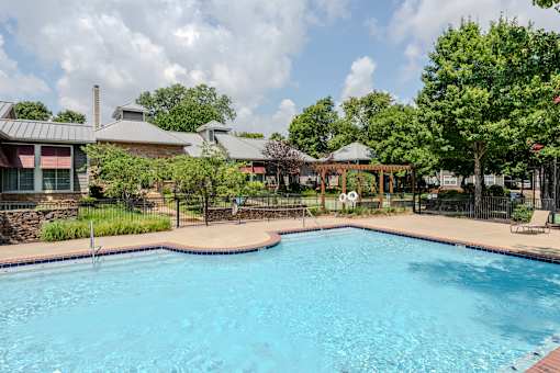 A large swimming pool in a backyard with a gazebo in the background.