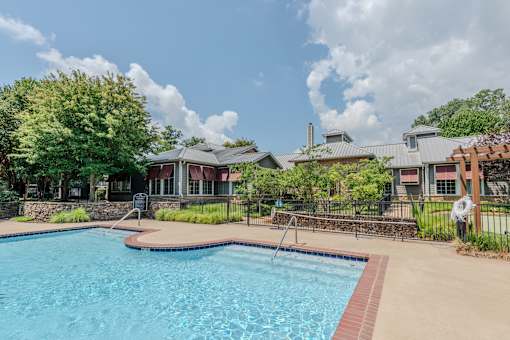 A swimming pool surrounded by a fence and a building in the background.