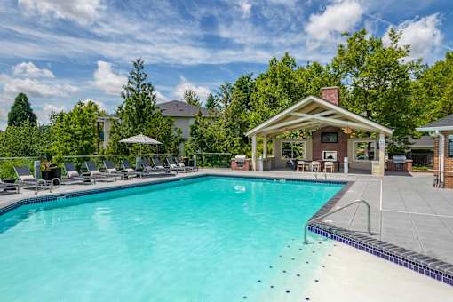 A swimming pool with a pavilion and sun loungers.