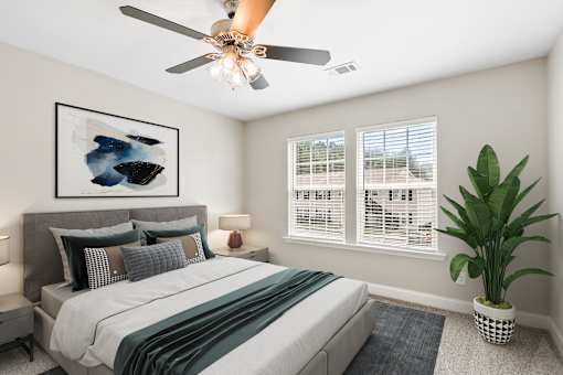 A bedroom with a bed, a ceiling fan, and a potted plant.