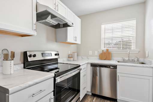 Modern kitchen with white granite cabinets and stainless steel appliances at Pooler Station apartments for rent in Pooler, GA.