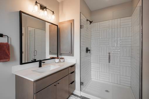 A bathroom with a sink, mirror, and shower.