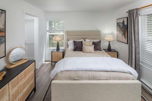 A bedroom with a large bed and a wooden dresser.
