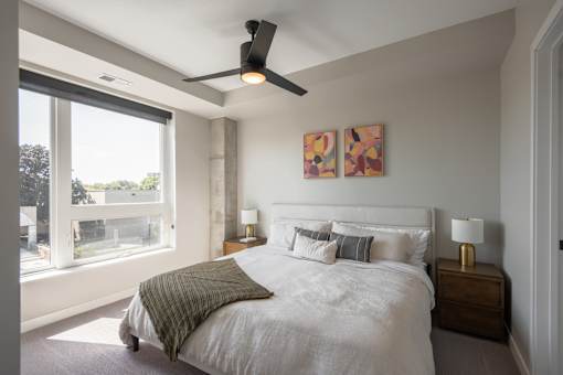 A bedroom with a large bed and a ceiling fan.